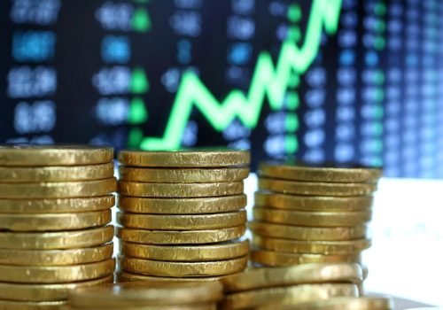 een stapel munt geld mnaar daarachter een grafiek