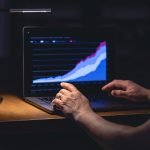 Zakenman, beurshandelaar, kijkt 's nachts naar het scherm van zijn laptop.