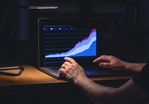 Zakenman, beurshandelaar, kijkt 's nachts naar het scherm van zijn laptop.